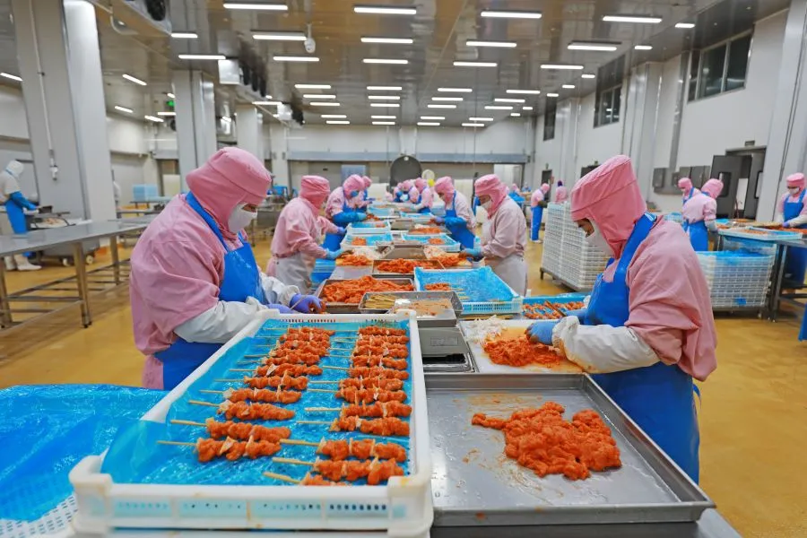 workers processing meat in factory